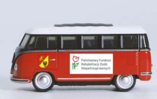 na zdjeciu zabawkowy autobus stylizowany na lata 60-te z logotypami PFRON i Powiatu Lwóweckiego