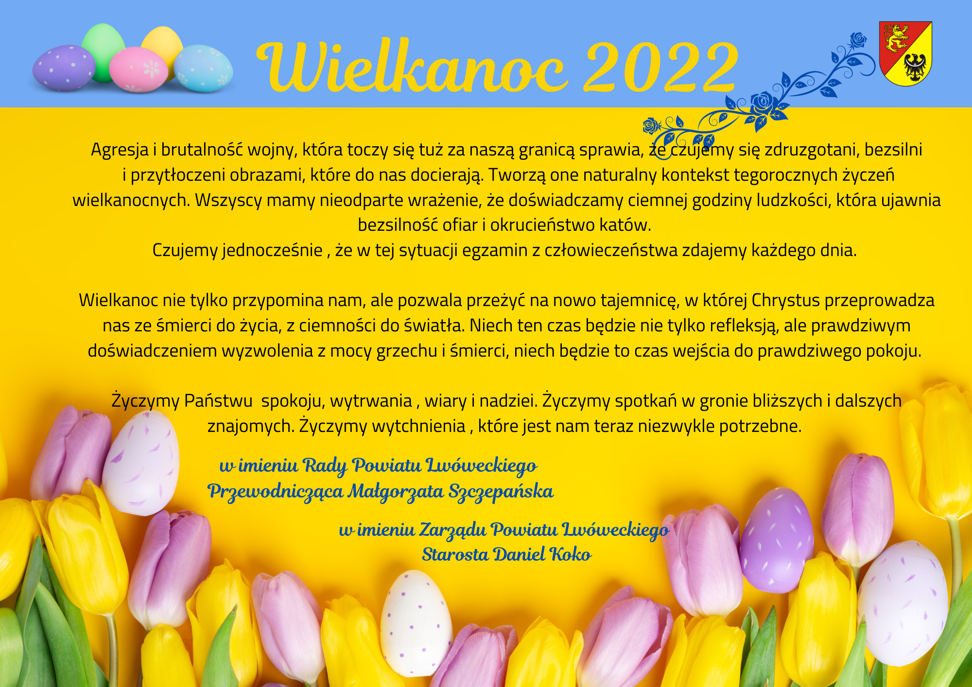 na niebieskim pasku od góry obrazka od lewej grafika pisanek, napis: Wielkanoc 2022, herb Powiatu Lwóweckiego, pozostała część na tle żółtym tekst życzeń (we wpisie) na dole obrazka białe, żółte i liliowe tulipany, gdzieniegdzie pisanka