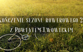 Na pierwszym planie rower leży w trawie, zachodzące słońce, napis: Zakończenie sezonu rowerowego 2022 z Powiatem Lwóweckim